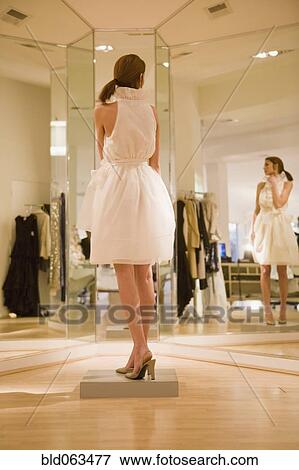 Stock Photo - Mixed race woman trying on dress in shop. Fotosearch