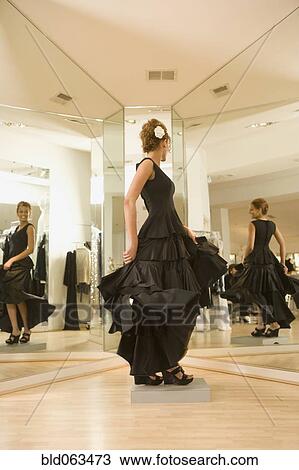 Stock Image - Mixed race woman trying on flamenco dress in shop. Fotosearch