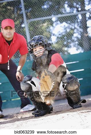Stock Photo - Multi-ethnic baseball catcher and coach behind home plate. Fotosearch
