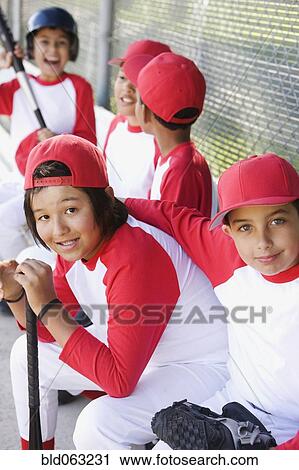 Stock Image - Multi-ethnic boys in baseball uniforms in dugout. Fotosearch