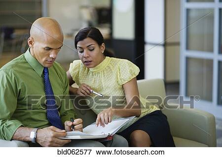 Stock Photo - Multi-ethnic business people discussing paperwork in office. Fotosearch