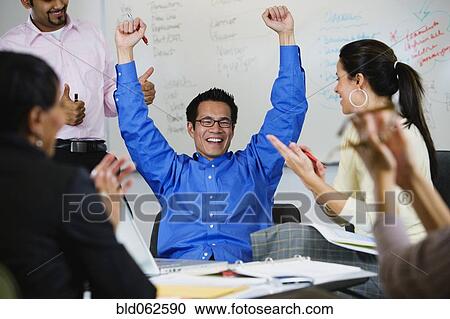 Stock Image - Multi-ethnic business people celebrating in meeting. Fotosearch