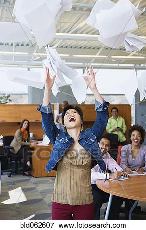 Stock Photo - Multi-ethnic business people throwing papers in air. Fotosearch