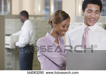 Stock Image - Multi-ethnic business people working on laptop in office. Fotosearch