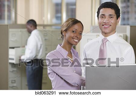 Stock Image - Multi-ethnic business people working on laptop in office. Fotosearch