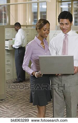 Stock Photo - Multi-ethnic business people working on laptop in office. Fotosearch