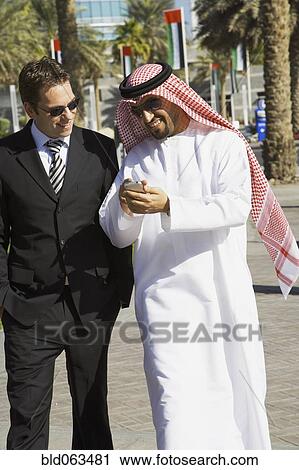 Stock Image - Multi-ethnic businessmen looking at cell phone. Fotosearch