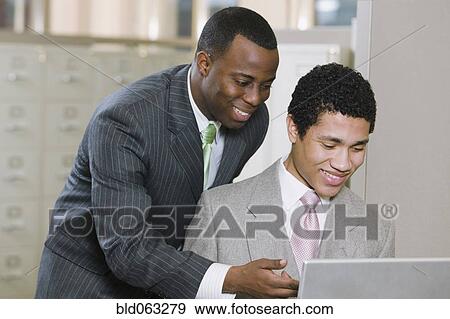 Multi-ethnic businessmen working on laptop in office View Large Photo Image Stock Photo - Multi-ethnic businessmen working on laptop in office. Fotosearch
