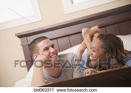 Stock Image - Multi-ethnic couple laying in bed. Fotosearch