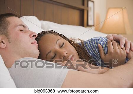 Stock Photo - Multi-ethnic couple sleeping in bed. Fotosearch
