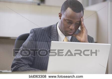 Stock Photo - Stressed African businessman working on laptop. Fotosearch