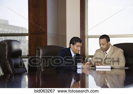 Stock Photo - Two businessmen working in executive conference room. Fotosearch