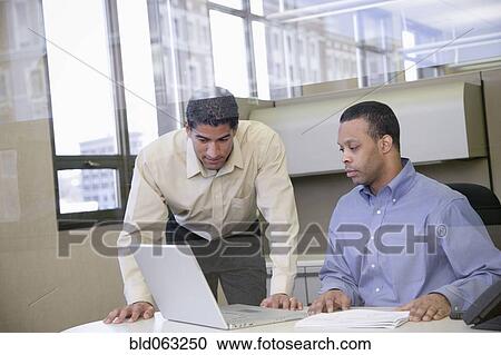 Stock Image - Two businessmen working in office. Fotosearch