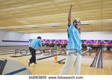Stock Photo - African woman cheering in bowling alley. Fotosearch