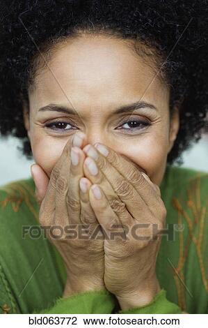 Stock Image - African woman covering her mouth. Fotosearch