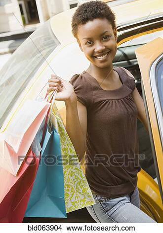 African woman entering taxi with shopping bags View Large Photo Image Picture - African woman entering taxi with shopping bags. Fotosearch