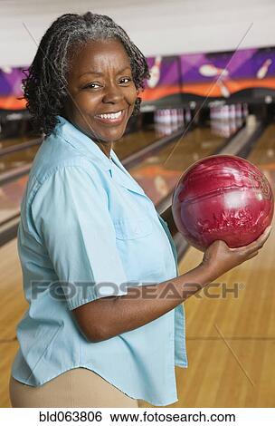 Stock Photograph - African woman holding bowling ball. Fotosearch