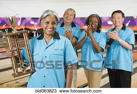 African woman holding bowling trophy while team applauds View Large Photo Image Stock Image - African woman holding bowling trophy while team applauds. Fotosearch
