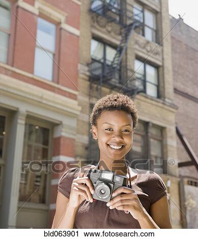Stock Image - African woman holding camera. Fotosearch