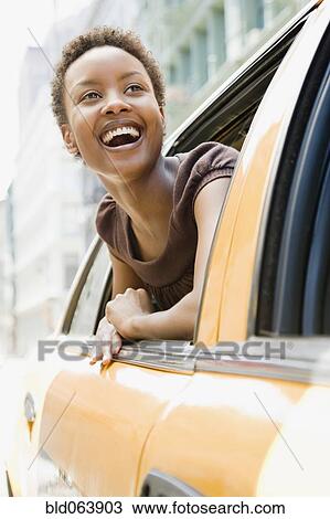 Stock Image - African woman looking out taxi window in wonder. Fotosearch