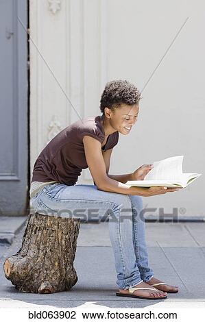 African woman sitting on tree stump and reading View Large Photo Image Stock Image - African woman sitting on tree stump and reading. Fotosearch