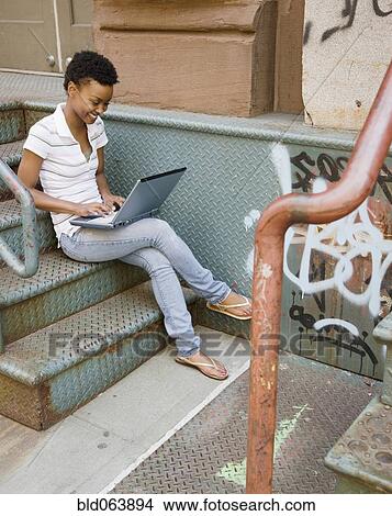 African woman sitting on urban steps with laptop View Large Photo Image Picture - African woman sitting on urban steps with laptop. Fotosearch