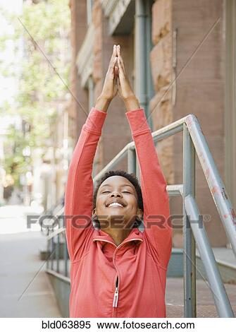 Stock Photography - African woman stretching on urban sidewalk. Fotosearch