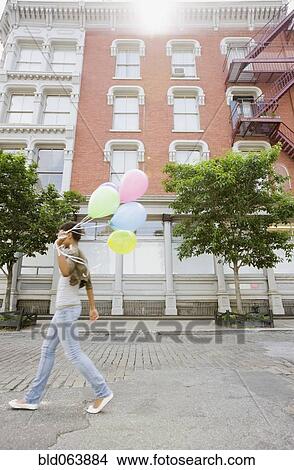 Picture - African woman walking with bunch of balloons. Fotosearch