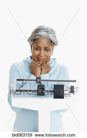African woman weighing herself on scale View Large Photo Image Stock Photo - African woman weighing herself on scale. Fotosearch