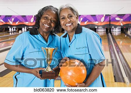 African women holding bowling ball and trophy in bowling alley View Large Photo Image Stock Image - African women holding bowling ball and trophy in bowling alley. Fotosearch