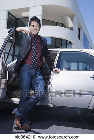 Stock Photo - Asian businessman leaning on car. Fotosearch