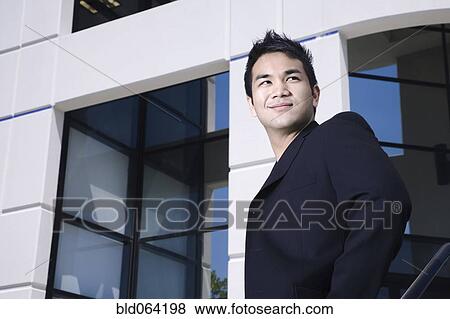 Stock Photo - Asian businessman outside office building. Fotosearch