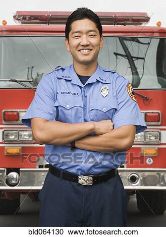 Stock Image - Asian firefighter next to fire truck. Fotosearch