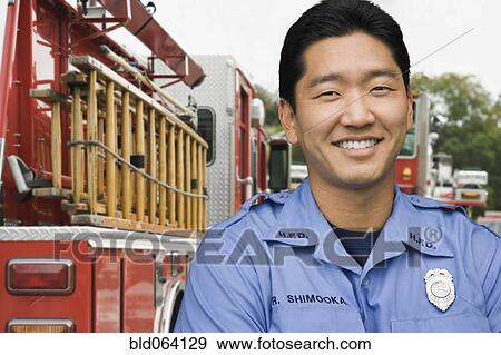Stock Photo - Asian firefighter next to fire truck. Fotosearch