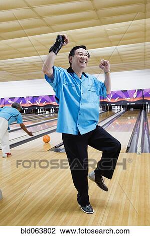 Asian man cheering in bowling alley View Large Photo Image Stock Image - Asian man cheering in bowling alley. Fotosearch