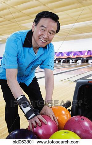 Asian man choosing bowling ball View Large Photo Image Stock Image - Asian man choosing bowling ball. Fotosearch