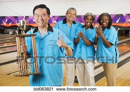Asian man holding bowling trophy while team applauds View Large Photo Image Stock Image - Asian man holding bowling trophy while team applauds. Fotosearch