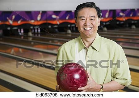 Stock Photo - Asian man in bowling alley. Fotosearch