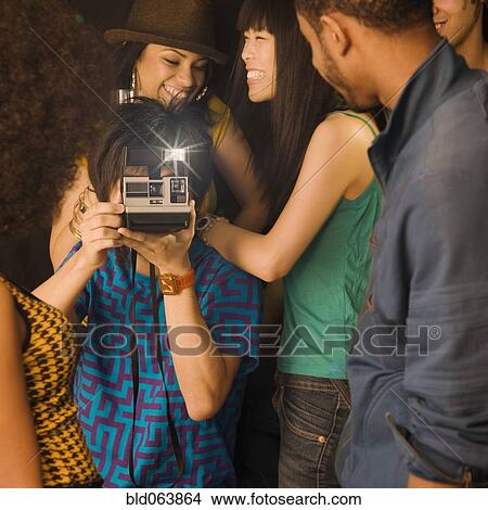 Picture - Asian man using instant camera in nightclub. Fotosearch