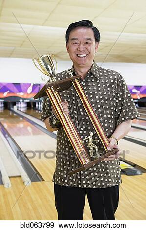 Stock Photo - Asian man with bowling trophy. Fotosearch