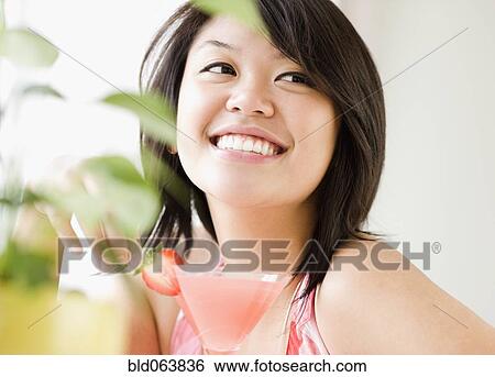 Stock Photograph - Asian woman drinking pink martini. Fotosearch