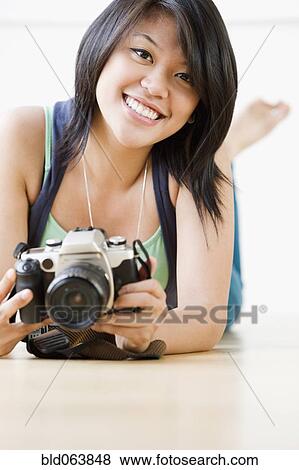 Asian woman laying on floor with camera View Large Photo Image Stock Photo - Asian woman laying on floor with camera. Fotosearch