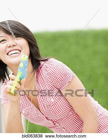 Stock Photo - Asian woman squirting toy water gun. Fotosearch