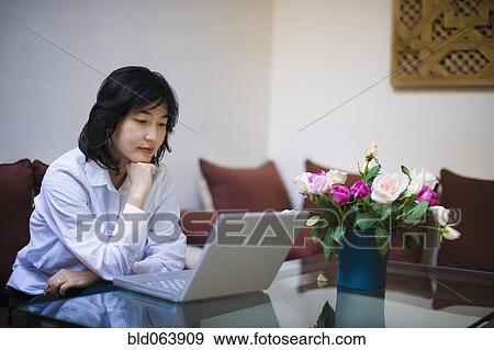 Asian woman using laptop in livingroom View Large Photo Image Stock Photo - Asian woman using laptop in livingroom. Fotosearch