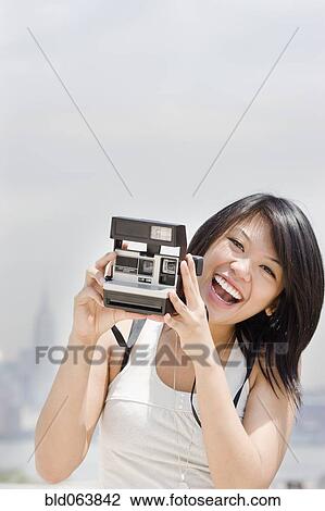 Stock Image - Asian woman with instant camera. Fotosearch
