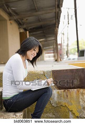 Asian woman writing and sitting on loading dock View Large Photo Image Stock Image - Asian woman writing and sitting on loading dock. Fotosearch