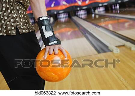 Stock Image - Close up of Asian man bowling in bowling alley. Fotosearch