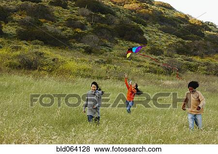 Friends flying kite in rural field View Large Photo Image Stock Photo - Friends flying kite in rural field. Fotosearch