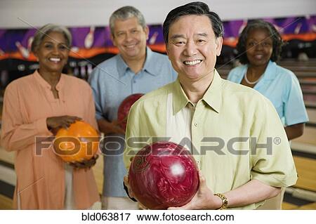 Stock Photo - Friends holding bowling balls in bowling alley. Fotosearch