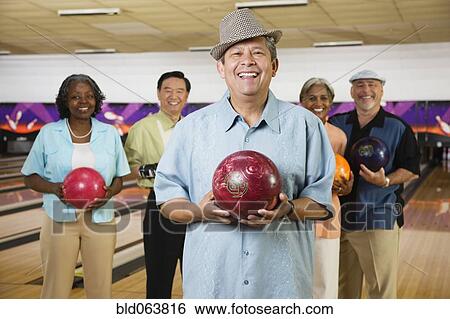 Friends holding bowling balls in bowling alley View Large Photo Image Stock Photograph - Friends holding bowling balls in bowling alley. Fotosearch